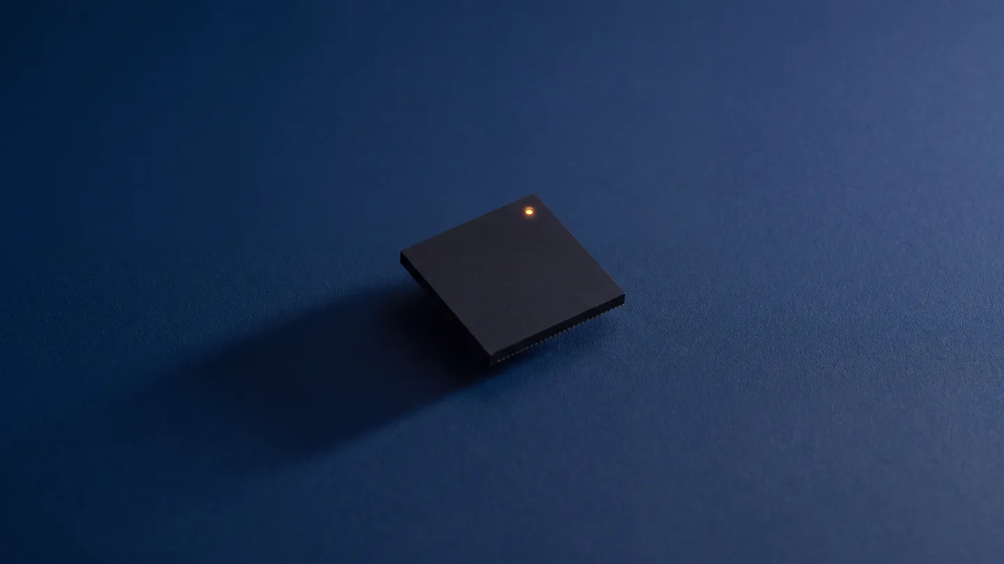 A single microchip with one small light, alone on a deep blue surface